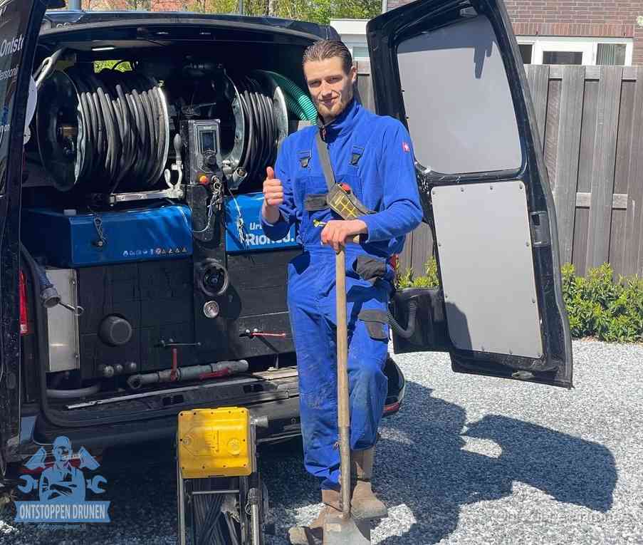 Een monteur bij de werkbus met grote hogedruk-slanghaspels, apparatuur voor hardnekkige afvoerverstoppingen in Drunen