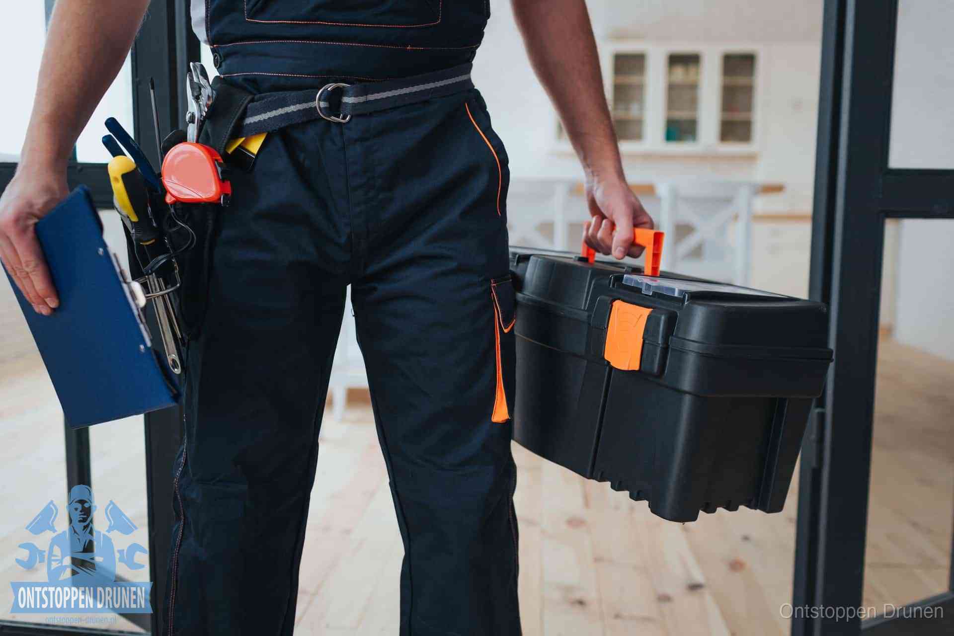 Een monteur met gereedschapsriem en klembord in een keuken, klaar om een transparante prijs voor het gootsteen ontstoppen in Drunen te geven