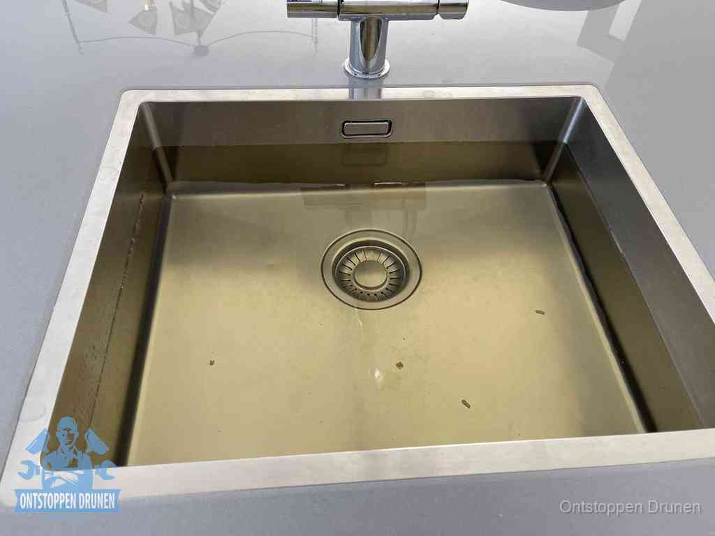 Stilstaand water in een rvs spoelbak dat niet wegloopt, een duidelijk signaal van een gootsteenverstopping in Drunen