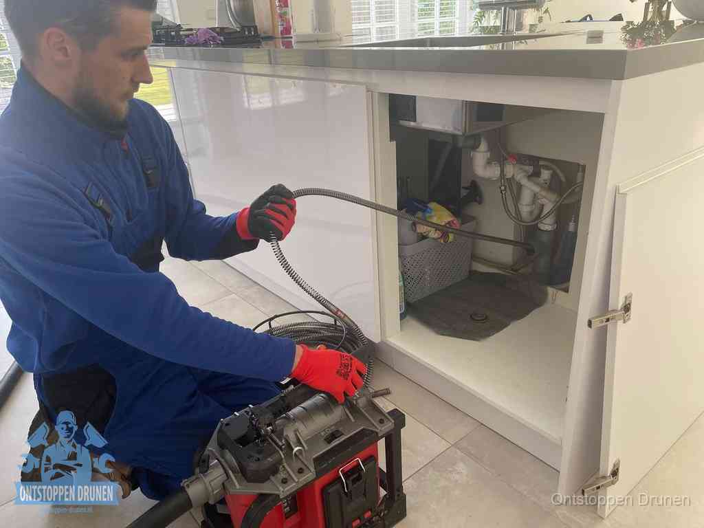 Een monteur reinigt de keukenafvoer grondig met een veermachine om terugkerende gootsteenverstoppingen te voorkomen in Drunen