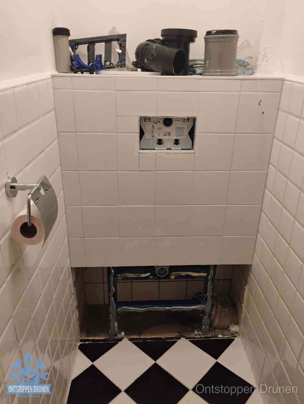 Een toiletruimte waar het hangtoilet en de inbouwreservoir-onderdelen zijn vrijgelegd voor onderhoud, periodiek nazicht voorkomt een wc-verstopping in Drunen
