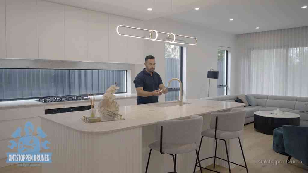 Een bewoner bij de keukenspoelbak die zelf aan de slag gaat met een verstopte gootsteen in Drunen